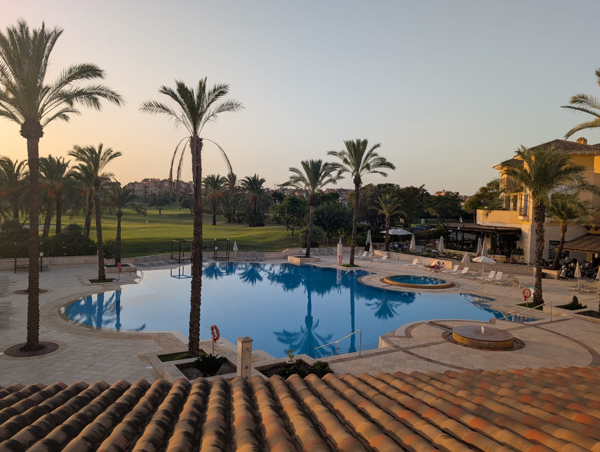 Poolanlage des Resorts mit Blick über den Golfplatz im Abendlicht
