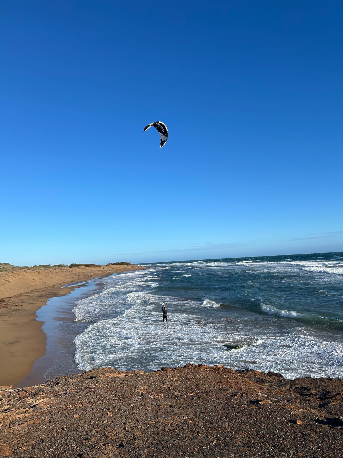 Kitesurfer am weiten Sandstrand an der spanischen Küste