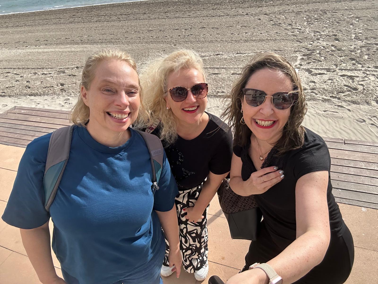 Drei Teilnehmerinnen lachen gemeinsam am Strand