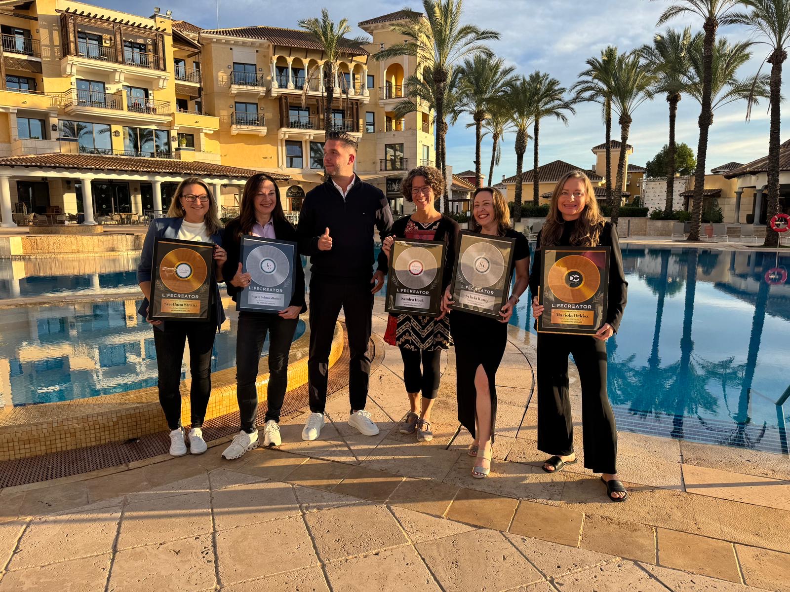 Teilnehmerinnen des THERACATION Retreats mit ihren Auszeichnungen am Pool des Resorts